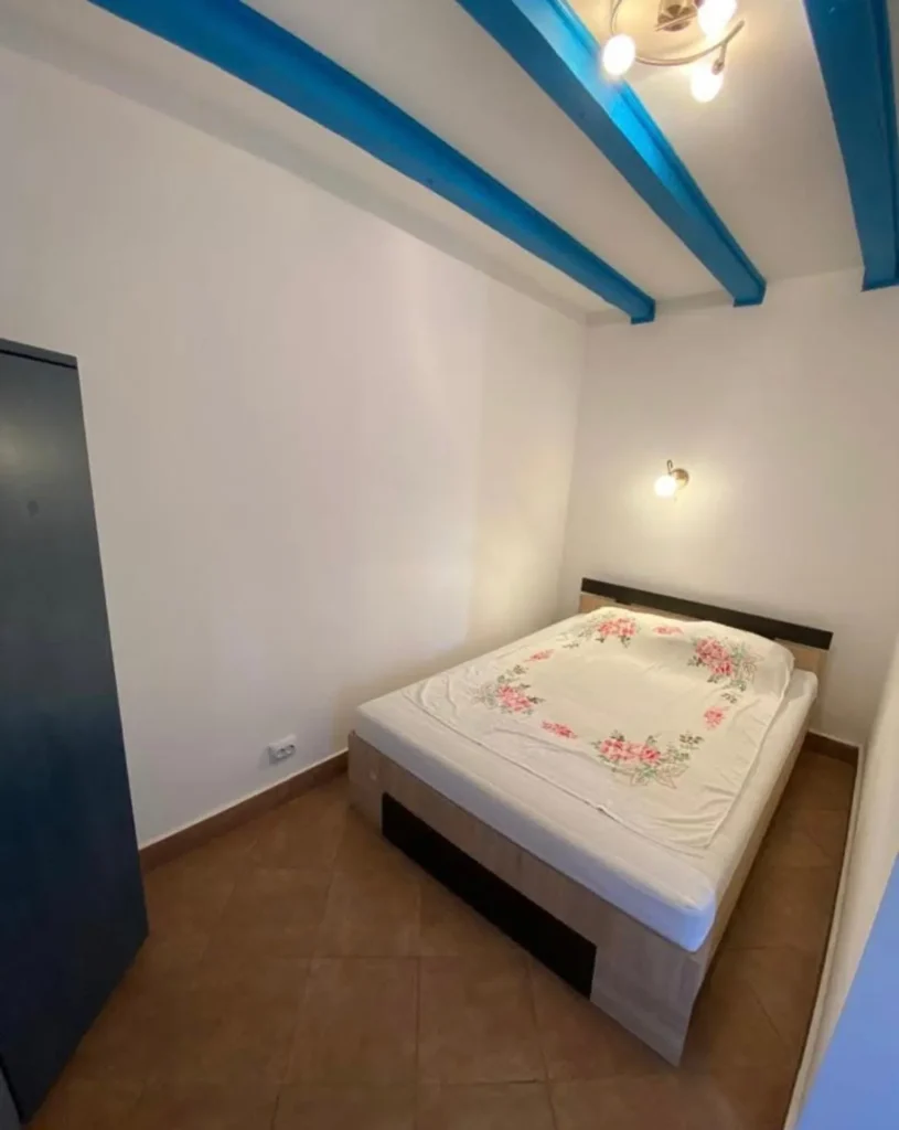 Single bedroom with double bed and blue ceiling.